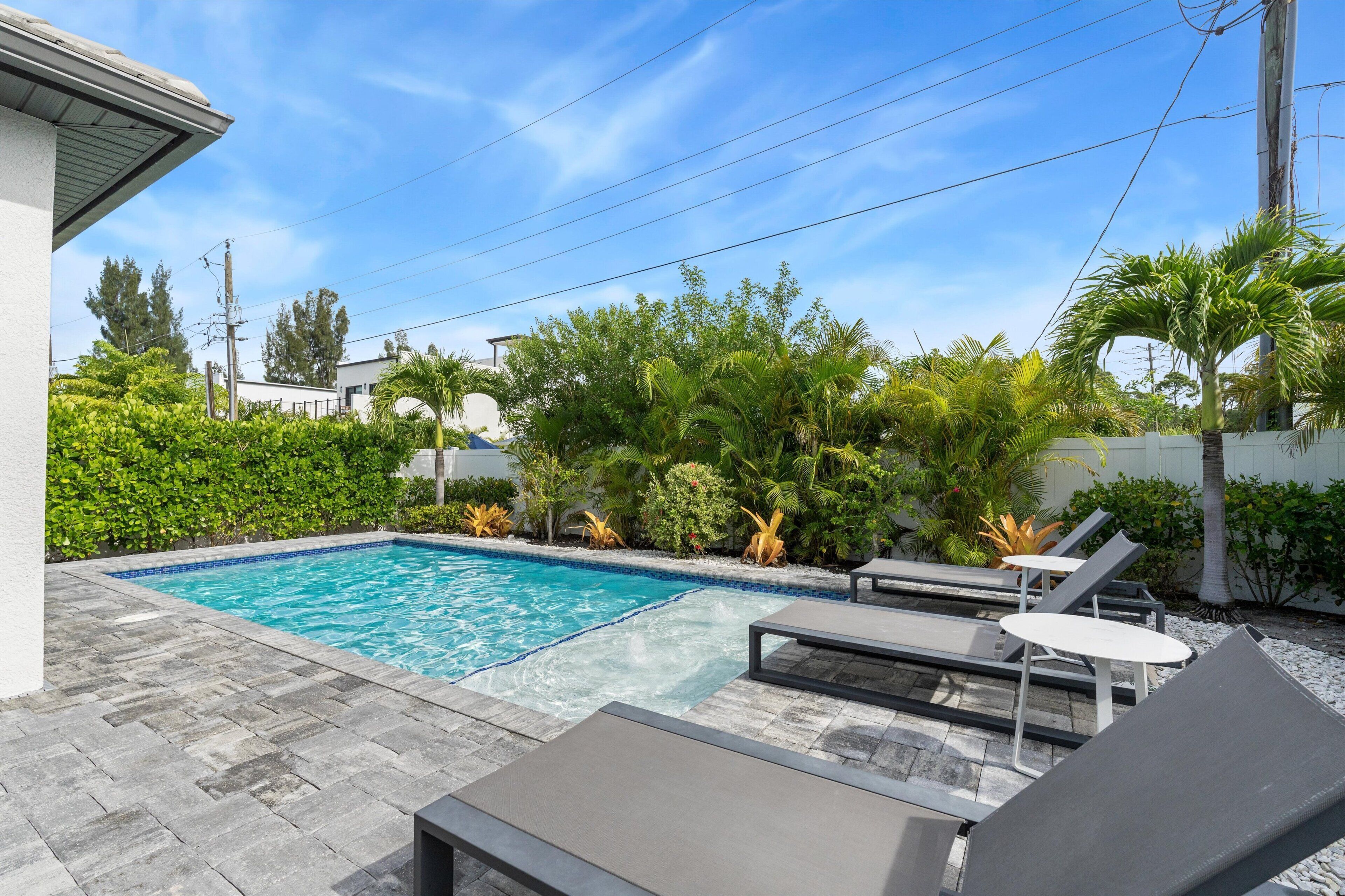 A swimming pool with lounge chairs and a tiled deck.