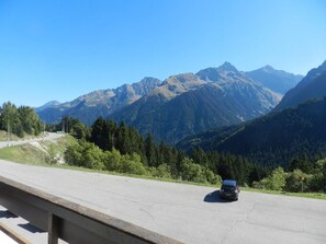 Un coche circulando por una carretera con un paisaje montañoso al fondo.