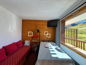 A compact room with a sofa, a small table, and a window with a view of a landscape.