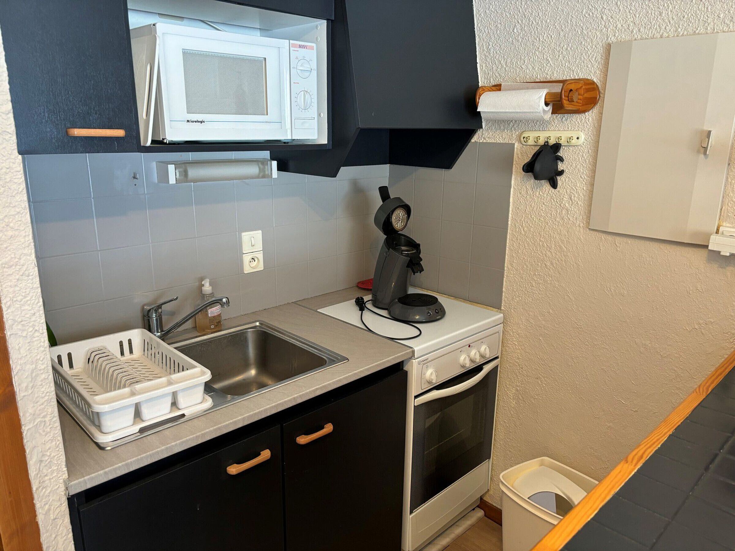 Eine kleine Küche mit Mikrowelle, Kaffeemaschine, Spüle und Backofen.