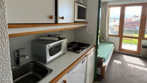 A compact kitchenette with a microwave, stove, sink, and a small refrigerator. - Functional studio 3/4 pers with balcony and direct slopes access (Belle Plagne)
