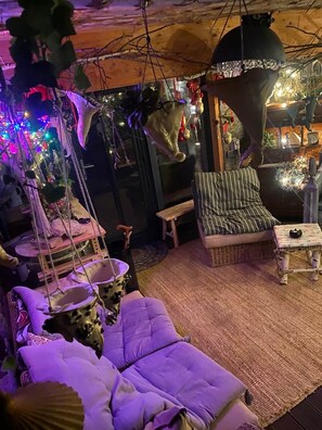 Una habitación acogedora con una silla colgante, un sofá mullido y una pequeña mesa.