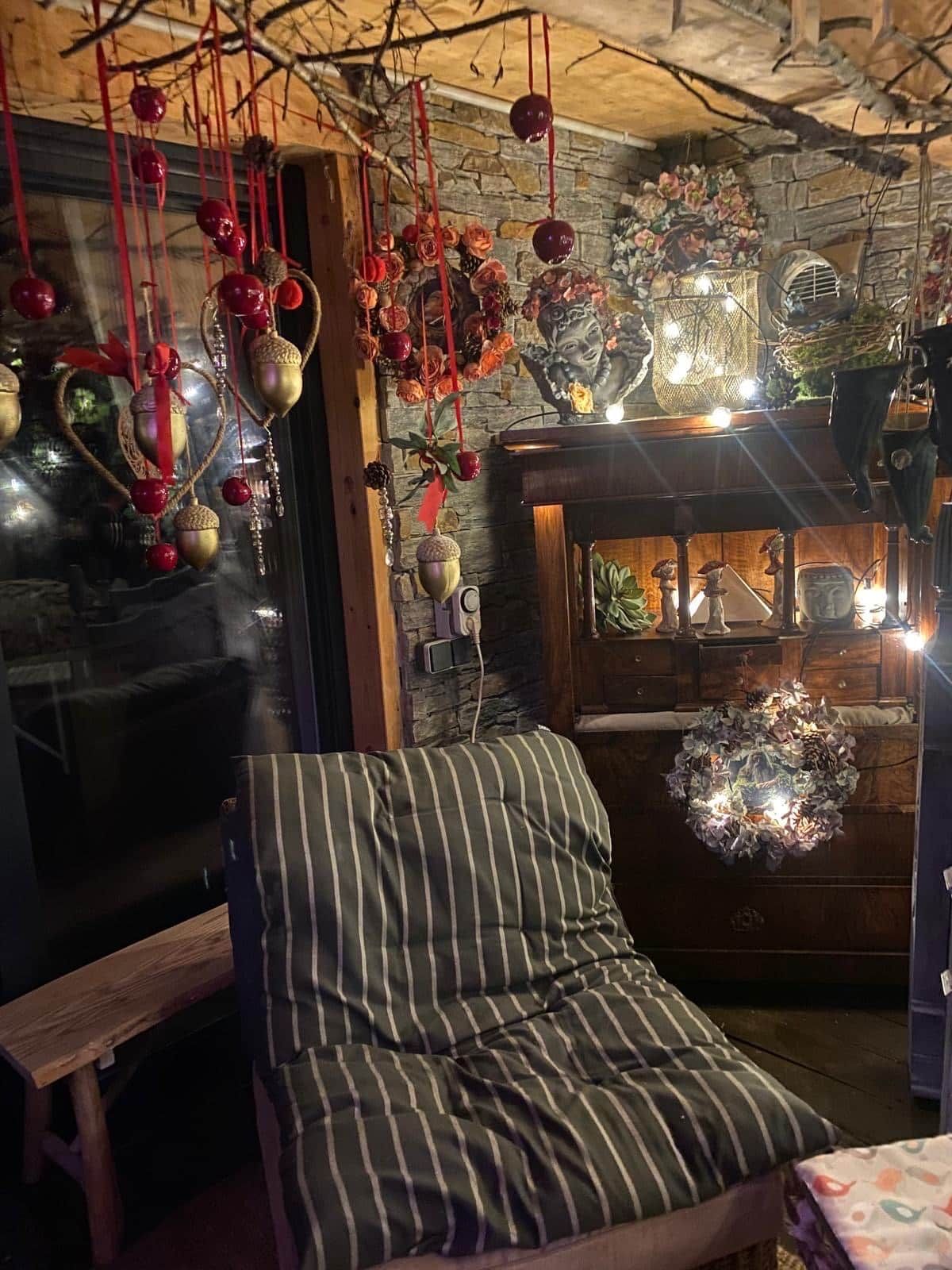 A cozy room with a striped chair, a wooden cabinet, and decorative hanging ornaments.