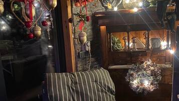 A cozy room with a striped chair, a wooden cabinet, and decorative hanging ornaments.