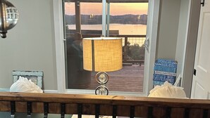 A room with a view of a body of water at sunset, a table with a lamp, and a sign with rules. - Lakeview Getaway with Stunning Sunsets with lake access (Newport)
