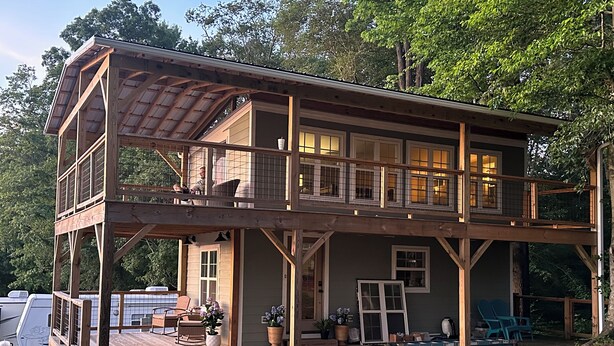 A two-story wooden house with a deck, a covered porch, and a fenced-in yard. - Lakeview Getaway with Stunning Sunsets with lake access (Newport)
