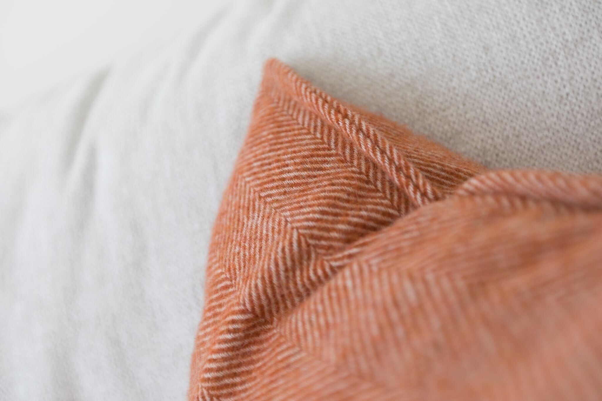 A close-up of a textured orange pillow on a white couch.