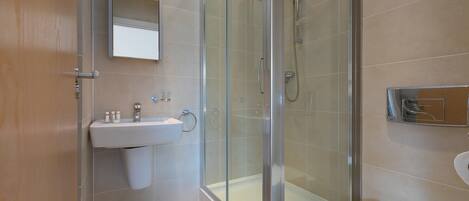 A modern bathroom with a glass-enclosed shower, a sink with a mirror above it, and a toilet.