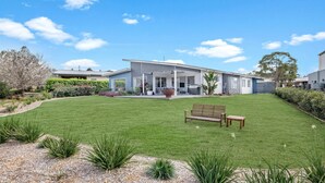 A modern house with a covered patio, a lawn, and a bench.