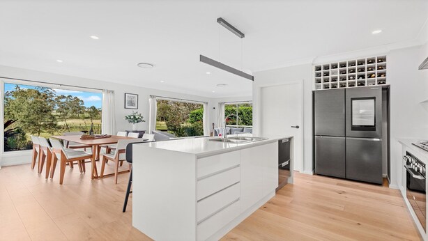 A modern kitchen with a central island, stainless steel appliances, and a dining area with a view of the outdoors.