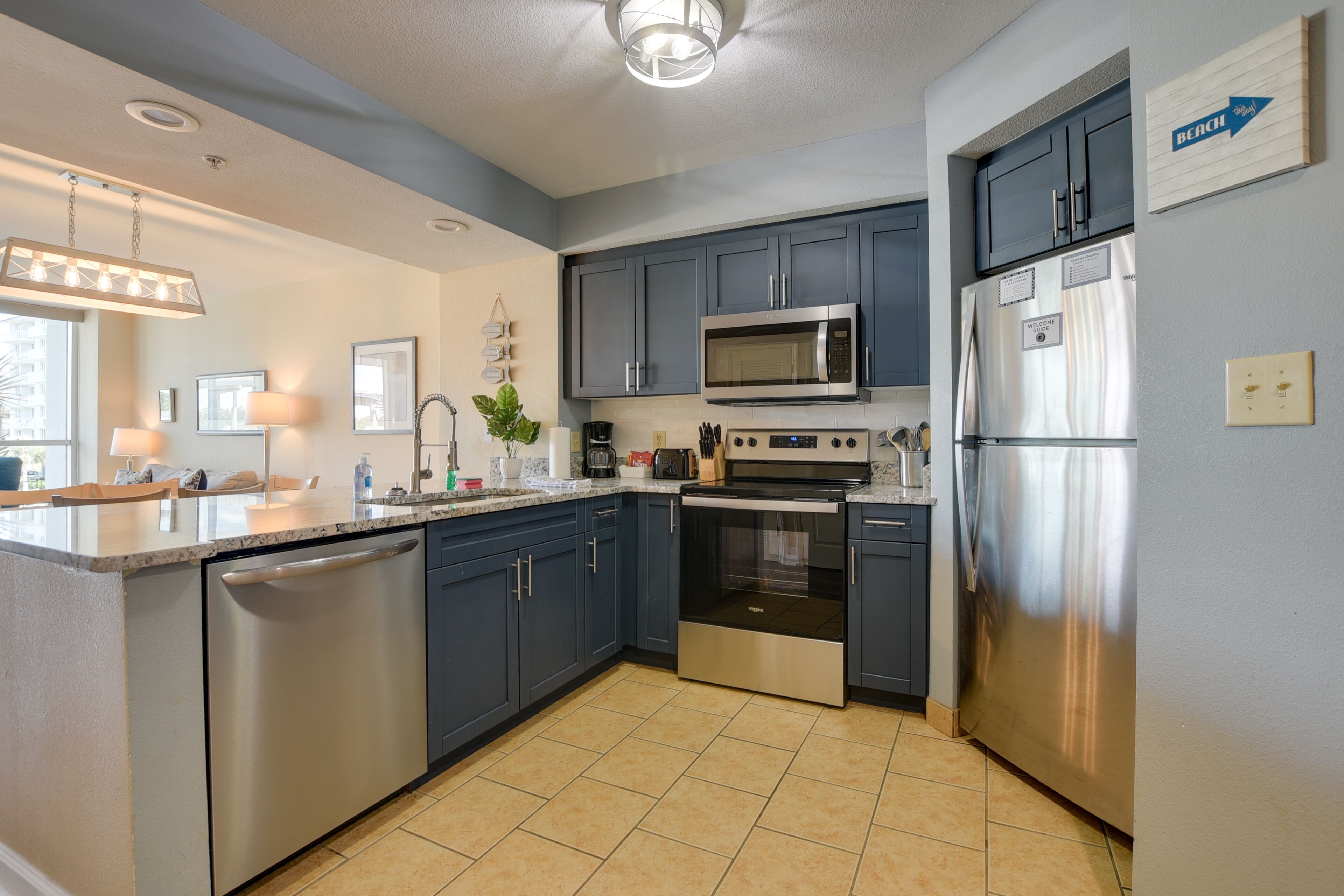 A modern kitchen with dark blue cabinets, stainless steel appliances, and a tiled floor.