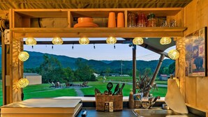 Une cuisine dotée d’une grande fenêtre donnant sur un paysage magnifique, de meubles en bois et de divers ustensiles de cuisine.