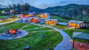 Un terrain de camping doté de plusieurs cabanes, d’un espace de restauration central et d’un foyer.
