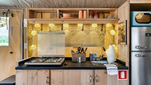 Une cuisine de taille réduite, équipée d’une cuisinière à gaz, de meubles en bois et d’un réfrigérateur en acier inoxydable.