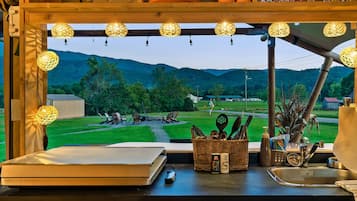 A kitchen with a large window overlooking a scenic landscape, wooden cabinets, and various kitchen utensils.
