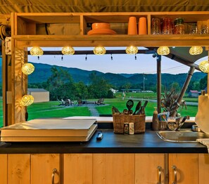 Eine Küche mit einem großen Fenster, das eine reizvolle Landschaft zeigt, mit Holzschränken und verschiedenen Küchenutensilien.
