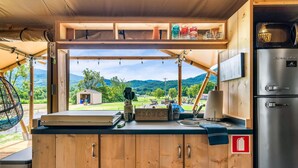 Cocina compacta con armarios de madera, un refrigerador de acero inoxidable y vistas a un paisaje montañoso.