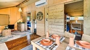 Un interior de madera con una mesa de comedor preparada para cuatro personas, un televisor y un ventilador de techo.