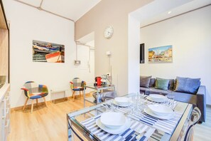A modern living room with a glass dining table set, a sofa, and colorful chairs.