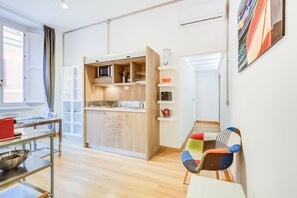 A compact kitchen with wooden cabinets, a microwave, and a coffee machine.