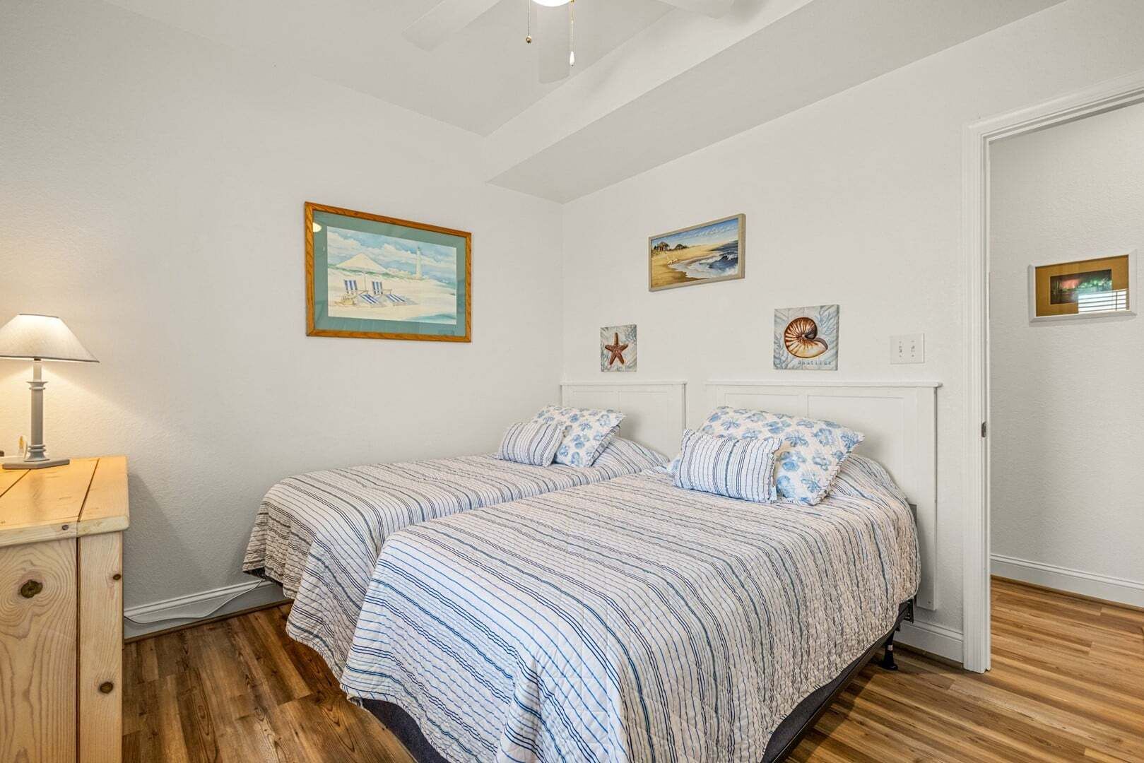 Een slaapkamer met twee bedden, een nachtkastje, een lamp en wanddecoratie.