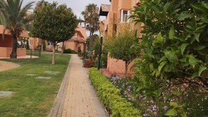 Un camino pavimentado bordeado de abundante vegetación y edificios con tejados de teja.