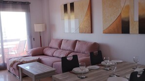 Una sala de estar moderna con un sofá rosa, una mesa de comedor preparada para cuatro personas y arte abstracto en las paredes.
