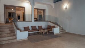 Un espacio de sala moderno con sofá integrado, una mesita y una escalera que sube a un nivel superior.