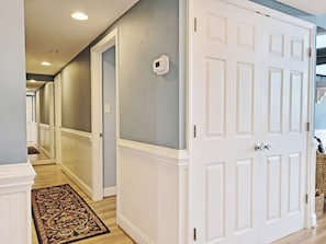 A hallway with a white door, a patterned rug, and a light switch on the wall.