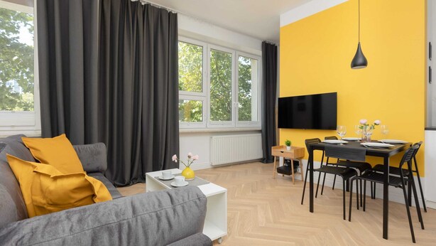 A modern living room with a sofa, a dining table, and a TV.