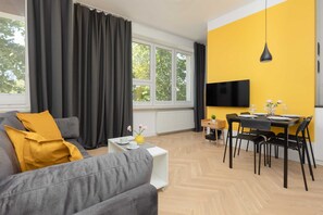 Moderni olohuone, jossa on sohva, ruokapöytä ja televisio.