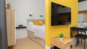 A modern bedroom with a bed, bedside tables, and a TV mounted on the wall.