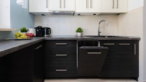 A modern kitchen with dark cabinetry, a stainless steel sink, and a coffee maker.
