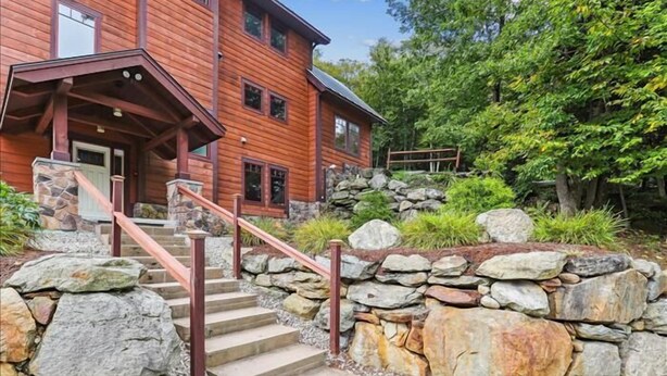 A wooden cabin with a stone staircase and a porch.