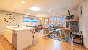 Een moderne woonkamer met een keukeneiland, een eethoek en een open haard.