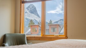 Een kamer met een groot raam, een bed en een stoel.