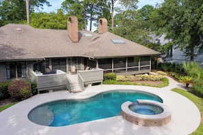 Une maison avec une piscine, un jacuzzi et un patio couvert.