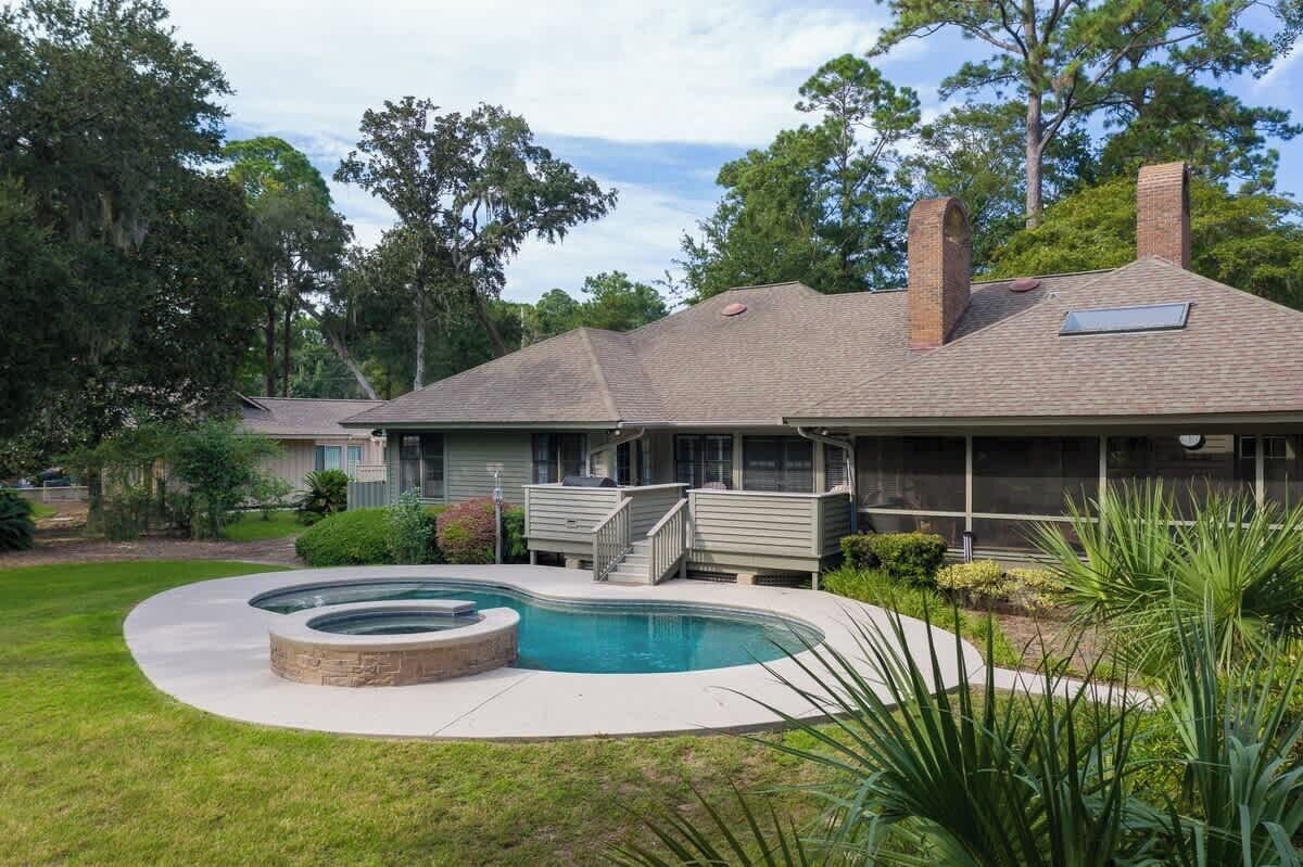 A house with a swimming pool, a covered patio, and a brick chimney.
