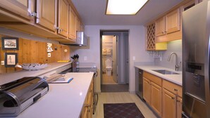 A modern kitchen with wooden cabinets, stainless steel appliances, and a central island. - Home Away From Home! Ski-in/Ski-out, Dog Friendly Condo w/ Fireplace & Views (Mt. Crested Butte)