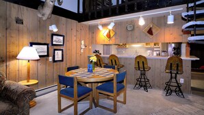 A cozy dining area with a wooden table and chairs, a lamp, and framed artwork on the walls. - Home Away From Home! Ski-in/Ski-out, Dog Friendly Condo w/ Fireplace & Views (Mt. Crested Butte)