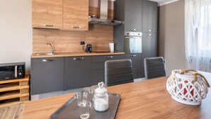 Een moderne keuken met grijze kastjes, een houten aanrecht en een eethoek met een tafel en stoelen.