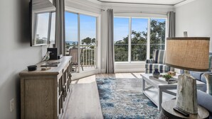 A modern living room with a large window, a ceiling fan, and a view of the outdoors.