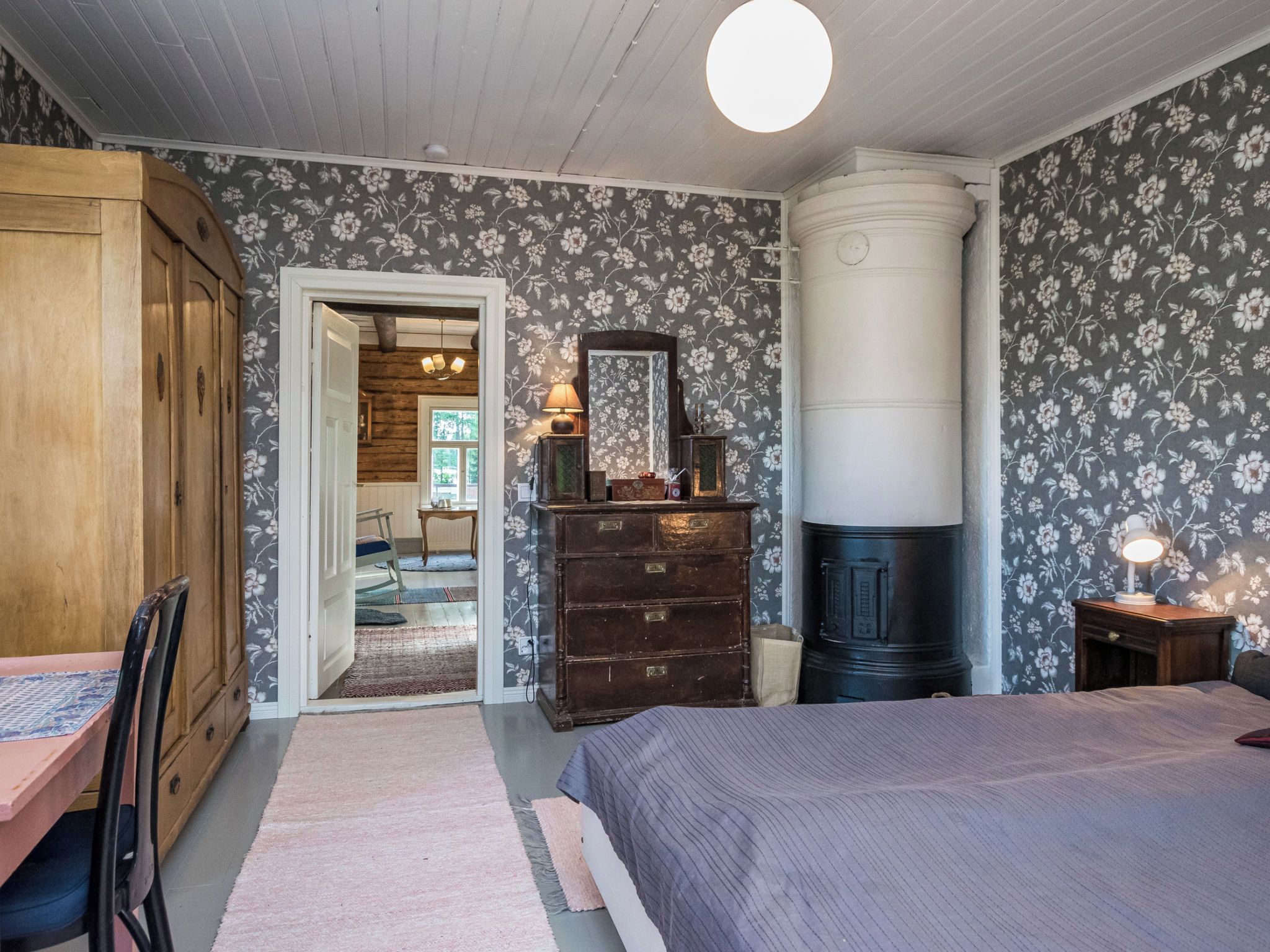 Une chambre à coucher avec un lit, une commode, un miroir et une cheminée.