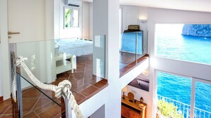 Ein Hotelzimmer mit Balkon und Blick auf das blaue Meer und eine Klippe.