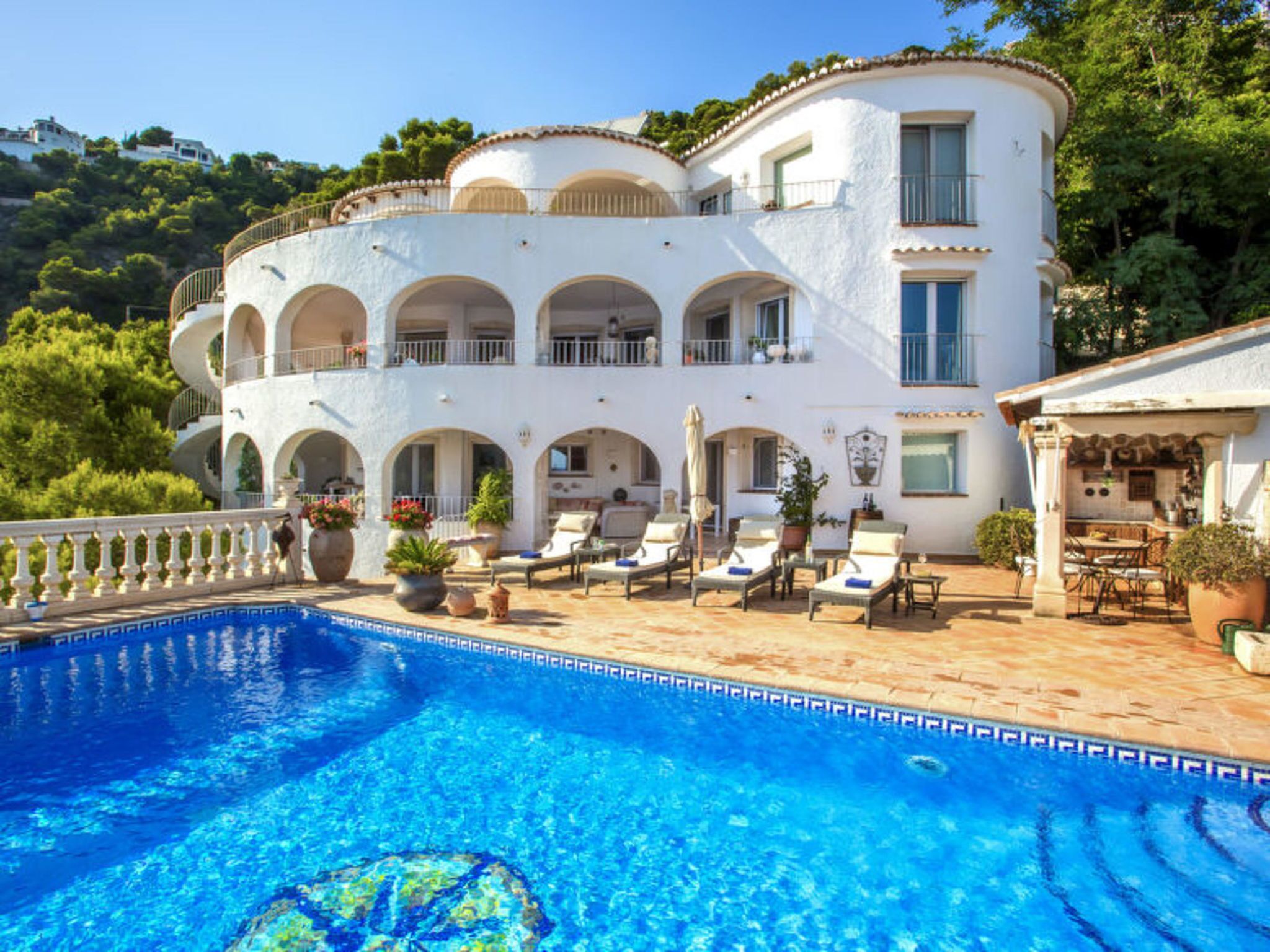 A two-story building with a swimming pool, outdoor seating, and a balcony.