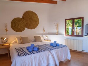 A bedroom with a bed, bedside tables, a window, and decorative wall hangings. - Can Masset by Interhome (Banyalbufar)