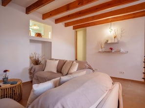 Une pièce chaleureuse avec un canapé, une petite table d’appoint ronde en bois et une étagère murale agrémentée d’objets décoratifs.