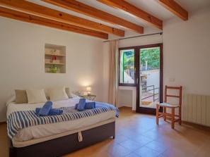 Une chambre à coucher avec un lit, une table de chevet, une lampe et une vue sur un balcon.