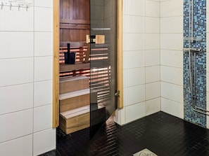 Et badeværelse med et trækommode, et sort badekar og et flisebelagt bruseområde.