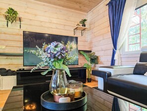 A modern living room with a flat-screen TV, a sofa, a coffee table with a vase of flowers, and a tray with candles. - Oravajärven talo (ent. suomela) by Interhome (Ranua)